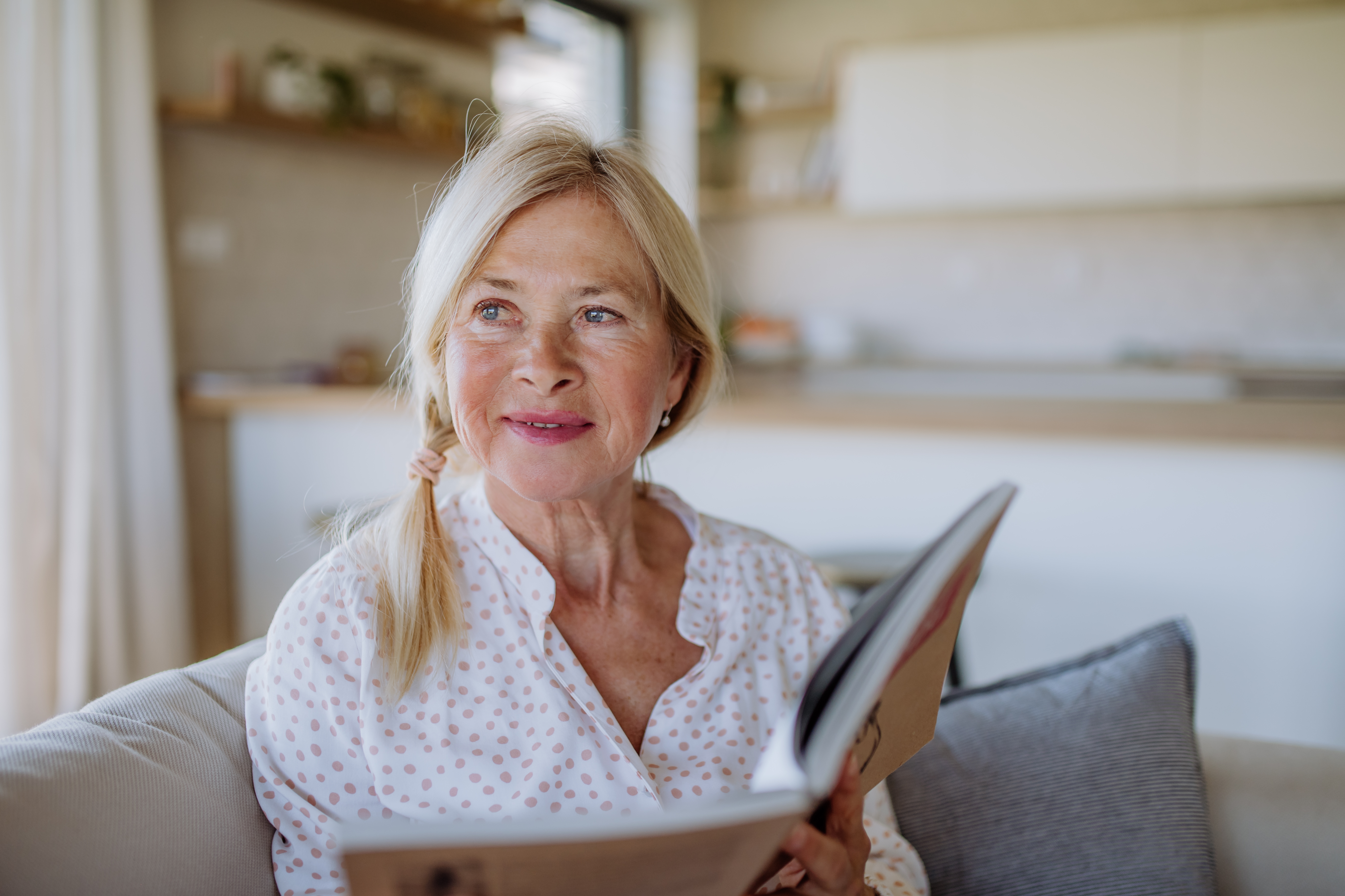 Kvinde sidder i sofa og ser eftertænksom ud