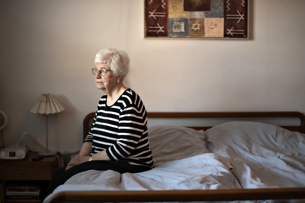Kvinde sidder på kanten af sengen