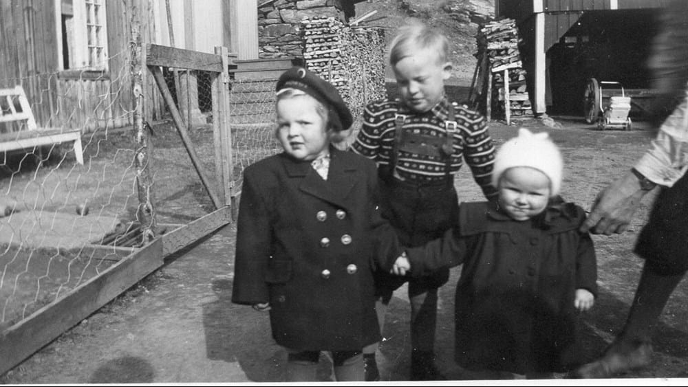 Jorunn Aune boede i sin spæde barndom på en gård udenfor Trondheim. Her står hun til højre med sin storesøster i hånden og sin bror i baggrunden. Begge søstre fik polio kort tid efter, men kun Jorunn fik lammelser.