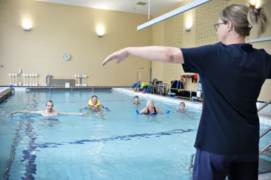 Svømmetræner instruerer øvelser for personer i svømmebassin