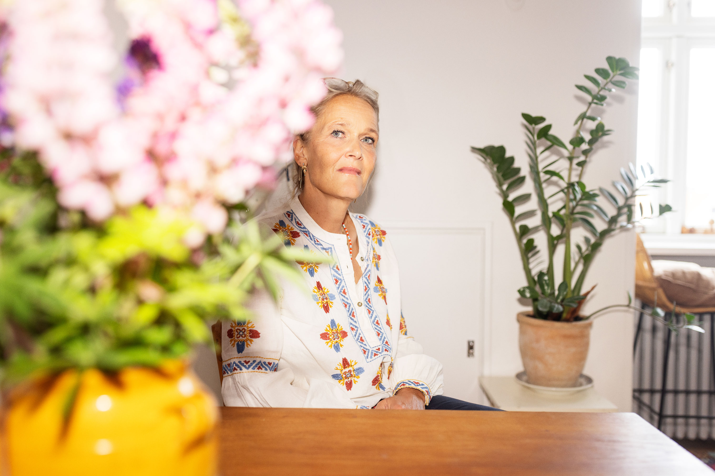 Kvinde sidder ved bord med blomster paa