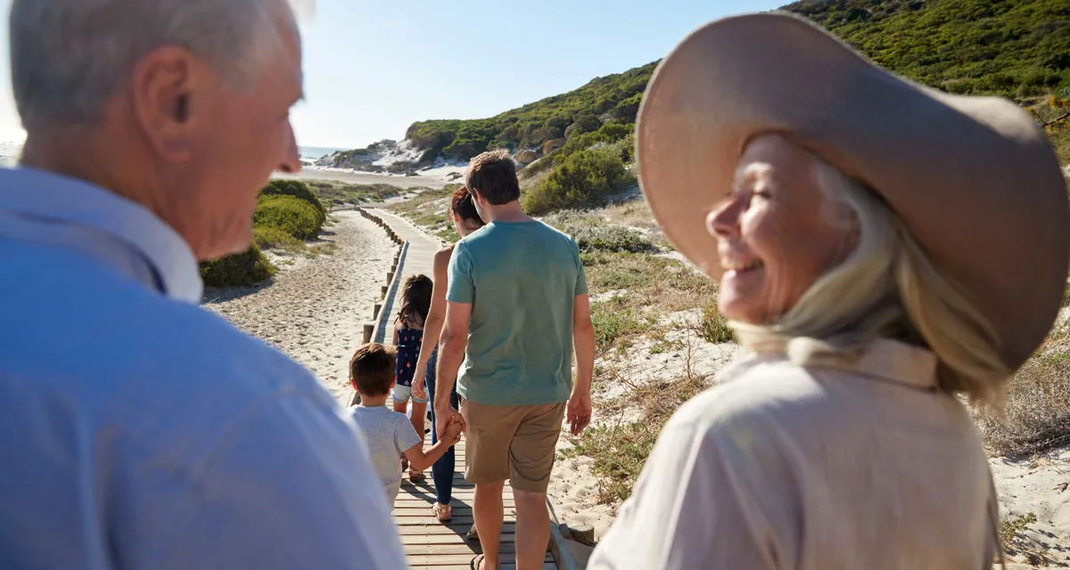 Flere personer unge som gamle går på tur ved en strand